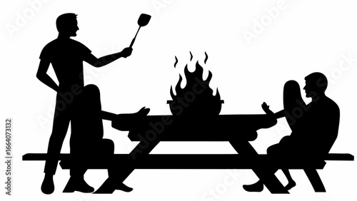 Silhouette of people gathered around a picnic table with a grill and a man holding a spatula up high