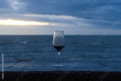 A single glass of chilled white wine on a table by the blue ocean and beach