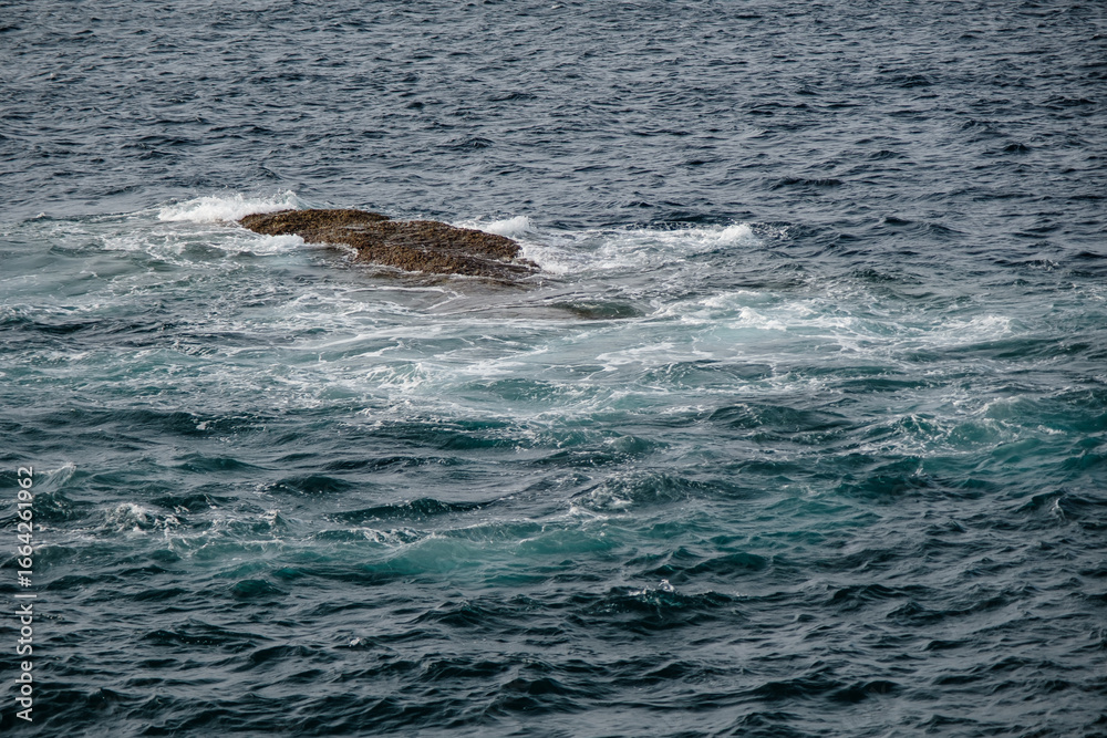 Naklejka premium small rocks at the open sea in cloudy sky summer day with empty copy space