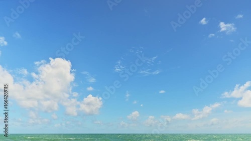Time lapse cloudy blue sky over the sea in summer time. Fast motion of cloudscape in beautiful sunny day above the ocean.