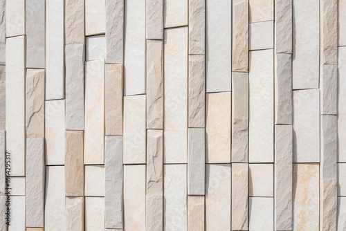 Close up of a wall made of vertical rectangular stone tiles in varying shades of white and beige