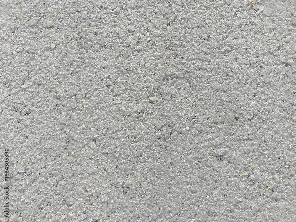 Fototapeta premium Rough Gray Asphalt Surface with Embedded Stones and Uneven Texture