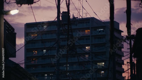 Tokyo Neighborhood Sunset with Power Lines Silhouetted Against Sky – Urban Tokyo street view with silhouetted power lines and glowing sky at sunset behind apartment buildings.