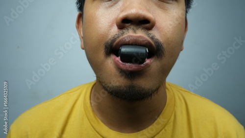Close-up of a man using a jawline training tool placed in his mouth, associated with mewing and facial muscle enhancement exercises.
