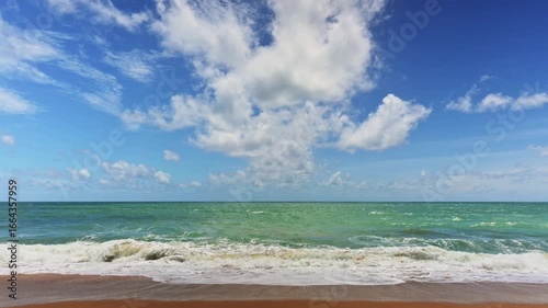 Cinematic scene of seashore with the wave crashing to the beach in Phuket Thailand. Stunning scenery of the coastal with emerald sea water under cloudy blue sky in the summer.