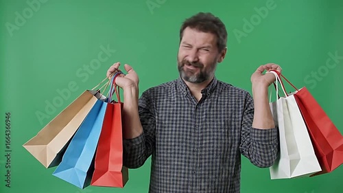 Man holding shopping bags in both hands on a green background