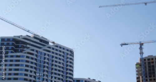 Real estate purchase concept. A male hand  holding the key to a new apartment  and throwing it to female hand with bracelets against the backdrop of a high-rise building under construction.