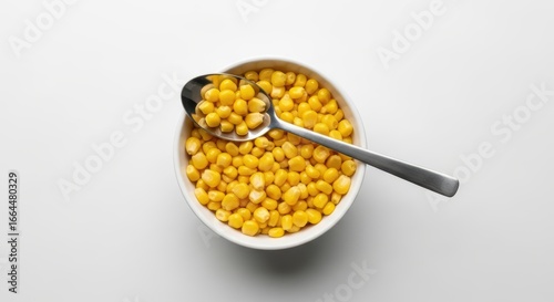 Bowl of sweet corn kernels with silver spoon on white background