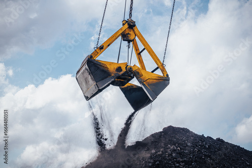 Valokuva Heavy machinery is actively involved in unloading coal from a large bucket at an industrial location