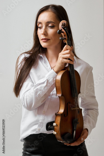 Elegant woman holding a violin, ready to perform music.