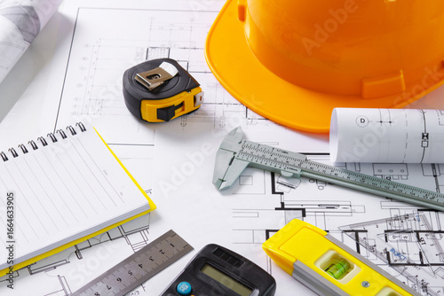 Architects concept, project house, Construction plans with yellow helmet and drawing tools on blueprints, of engineering tools on work table,