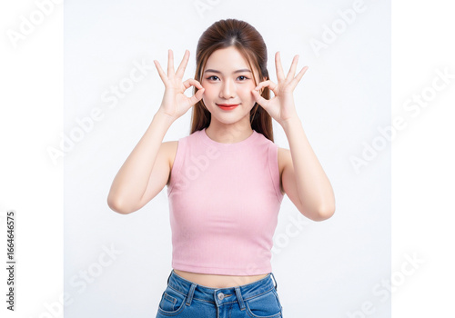 Playful Asian woman making glasses with OK hand gestures over her eyes.