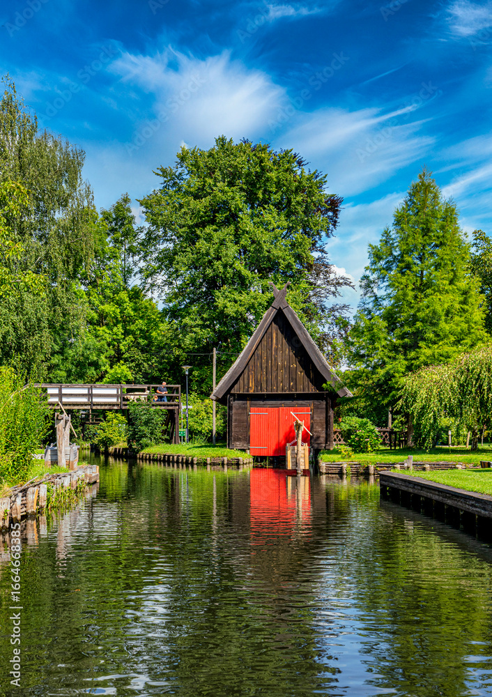 Fototapeta premium Tourismus in Brandenburg, Landschaft mit Fließgewässern, Häusern, Kähnen, Kajaks und Waldgebiet im Spreewald in Lübbenau und Lehde, Brandenburg, Deutschland