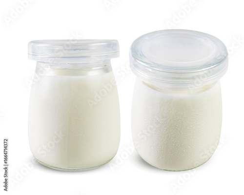 Two jars of homemade yogurt on a white background, one upright and one tilted