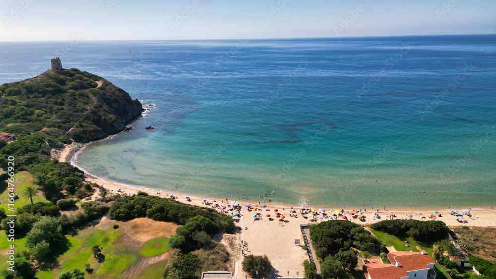 Fototapeta premium Drone View of Sardinia Shoreline with Idyllic Beach and Turquoise Waves. Small castle on the top of the hill by the shore.