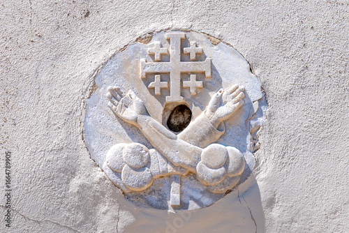 The Jerusalem Cross or Crusader Cross with two hands on each side of the cross representing Jesus and St. Francis of Assisi carved in stone on Saint John's Baptist Church in the old city of Acre, Akko