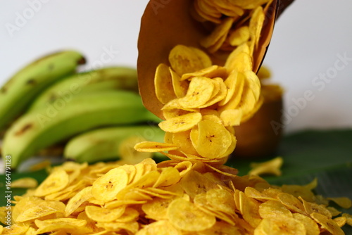 Foto Golden plantain chips spill from paper cone
