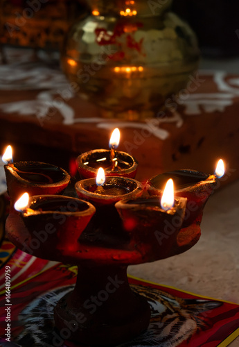 Traditional clay oil lamps glowing brightly during a Diwali (Hindu festival) poojan at home temple, symbolizing light, devotion, and purity and victory of divine over evil.