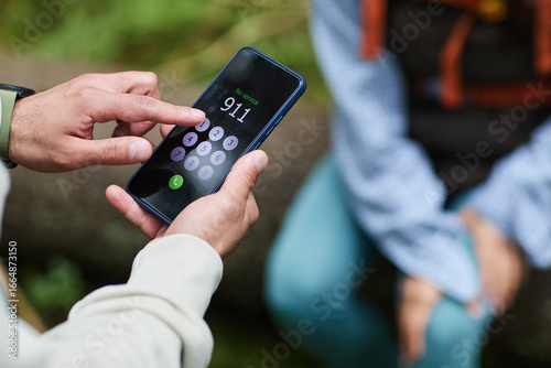 Bild auf Leinwand Young adult Caucasian man holding smartphone dialing emergency number 911 outdoo