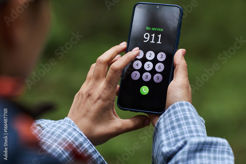 Tableau sur toile Caucasian young adult man holding smartphone outdoors dialing emergency number 9
