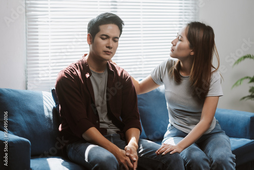 Tableau sur toile Young woman comforting her sad boyfriend while sitting together on a sofa at hom