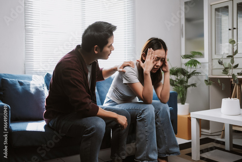 Foto Young man comforting his sad girlfriend while sitting together on the sofa, offe