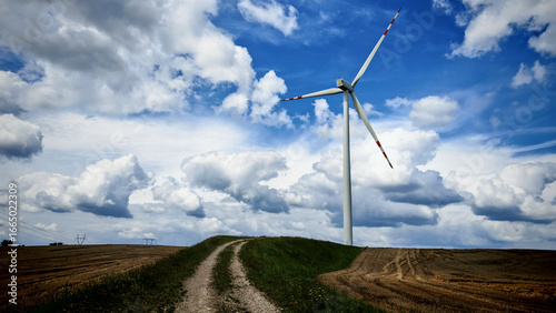 wind turbine in a field with clouds in the background