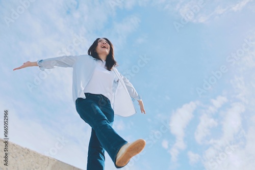 happy young asian woman jumping in the air under the blue sky background.