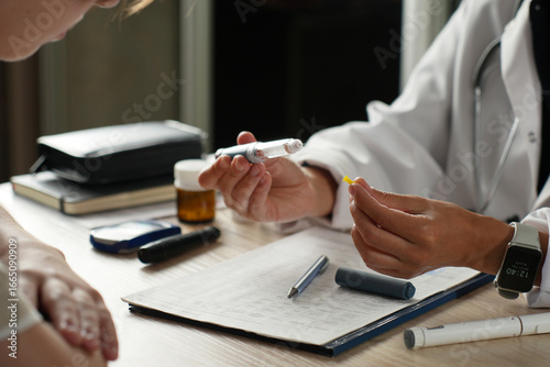 Close-up of doctor showing how to use insulin pen to patient