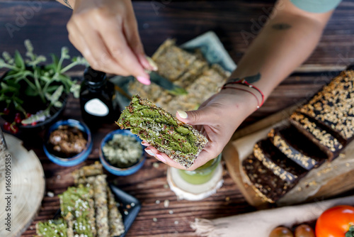 Woman hands spreading home made basil pesto on home baked gluten free bread