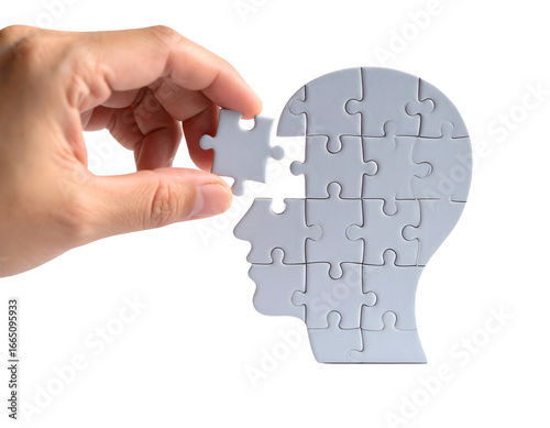 A hand places the final puzzle piece to complete a human head shape, symbolizing thought and understanding.