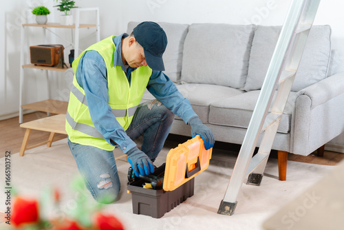 Bilde på lerret Professional handyman in reflective vest kneeling in living room unpacking tool