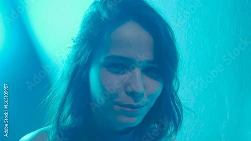 Beautiful young woman is dancing in party. Neon, blue and red light in studio shot, club and music with woman concept. Multicolored skin, ultraviolet light.