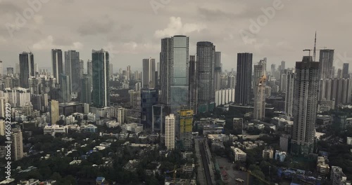 Cinematic aerial view of the Mumbai city skyline of Maharashtra, India, during the monsoon season, with dramatic clouds and top shots of moving cars, captured from above the clouds.