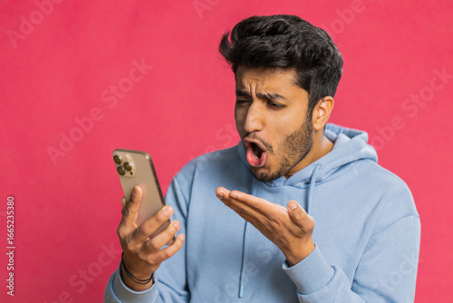Fotografie Upset sad Indian man use smartphone typing browsing, play game, loses, surprised by sudden lottery results bad fortune loss fail unlucky news