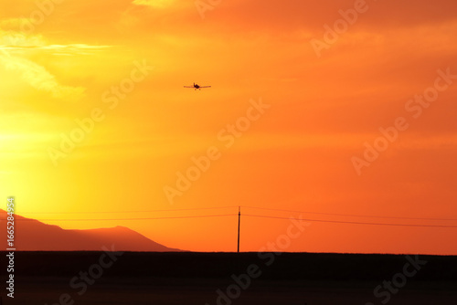 A bright red sunset among the mountains. The silhouette of an airplane is visible against the background of sunset