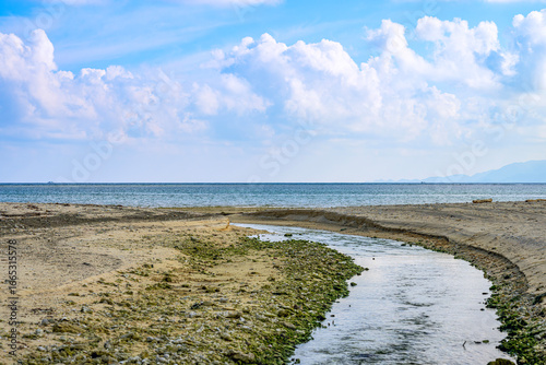  海へと流れる小川と青空が美しい石垣島の穏やかな海辺の風景
