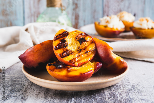 Delicious grilled peach halves on a plate on the table closeup