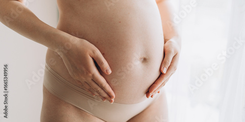 Wallpaper Mural Close up of a cute pregnant belly. Pregnant woman holds hands on belly touching her baby caring about her health. Motherhood concept Torontodigital.ca