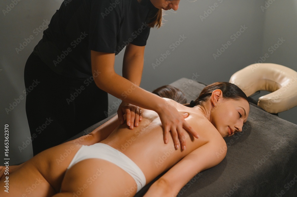 Obraz premium Masseur doing massage on woman back in the spa salon