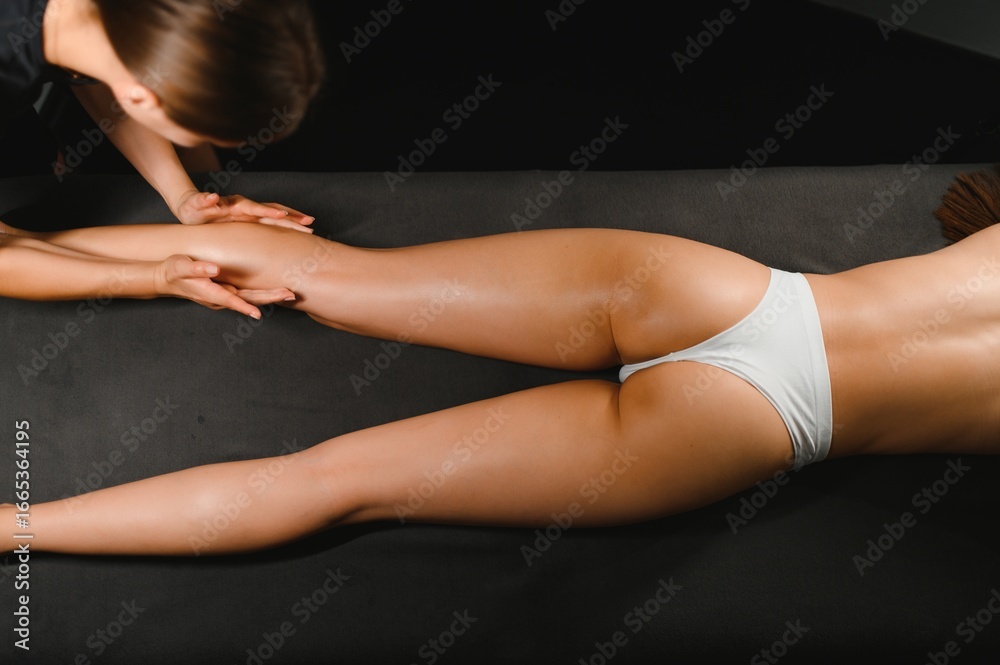 Obraz premium Lymphatic drainage massage of legs and lower legs. Female feet in the hands of a masseur