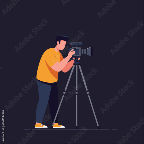 A male videographer in a yellow shirt and blue pants operating a professional video camera on a tripod.