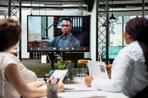 Fotografia Recruiters team and male candidate engage in a video call discussion with webcam and high tech tools, reviewing the resume and assessing job search progress during a remote interview conference
