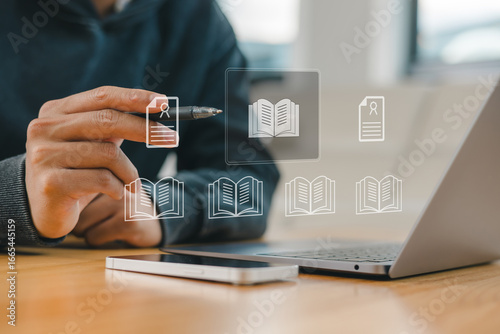 Digital library and e-learning concept with businessman using laptop and futuristic book icons, symbolizing online education, virtual knowledge, and smart technology for modern learning systems.