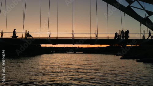 Silhouettes of people on the Humber River bridge against a summer sunset