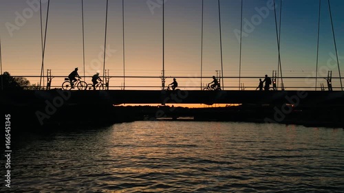 Cyclists and pedestrians cross the Humber River Bridge against a summer sunset