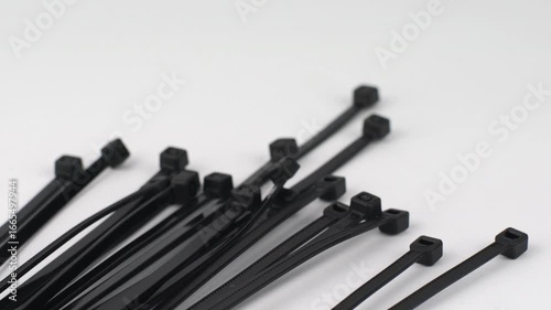Close-up of many black cable ties on a white surface, ideal for organization and fastening tasks in various settings.