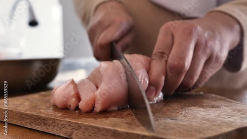 Asian muslim woman cutting chicken breast meat. Meal preparation