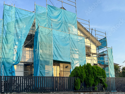 住宅の外壁塗装のための足場と青いネット