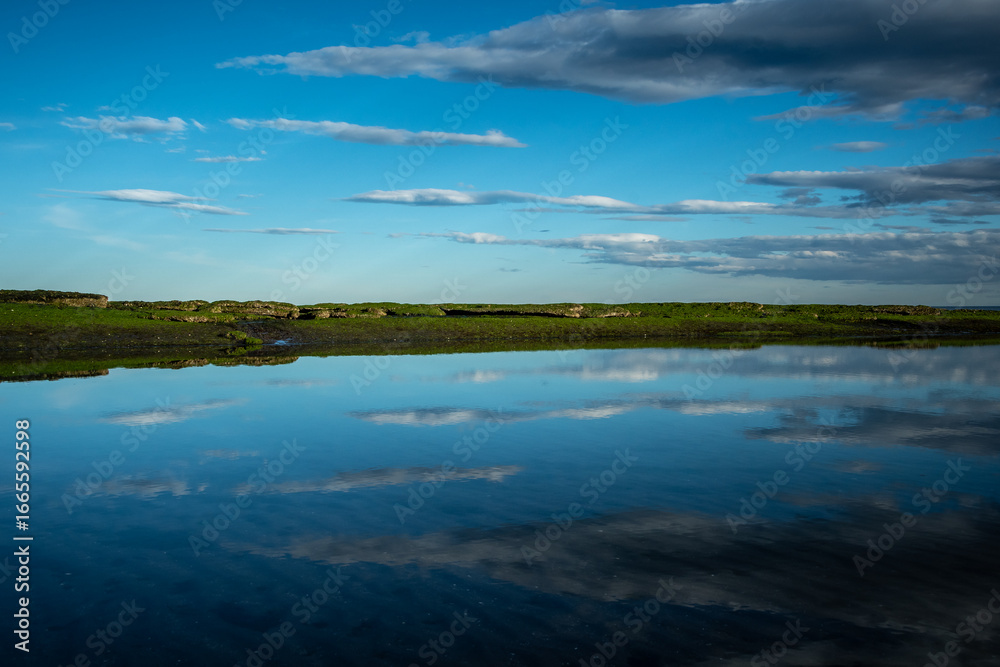 Fototapeta premium simetria entre un grupo de nubes del cielo que se ve reflejado en el mar 